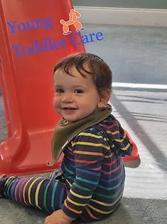 Young toddler smiling while sitting in a bright early learning classroom